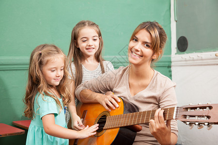 幼儿园的音乐课老师弹吉他背景图片
