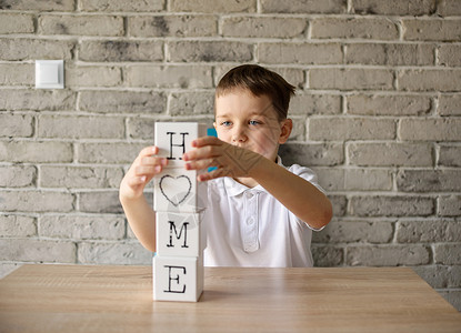 男孩玩木砖用字母写字回家穿着白图片