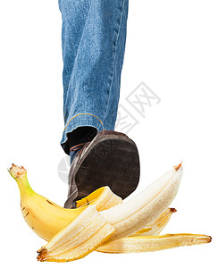 穿着牛仔裤和棕鞋踩香蕉的男左腿和棕鞋脚背景图片