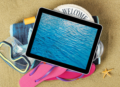 沙滩上的平板电脑和沙滩配件图片