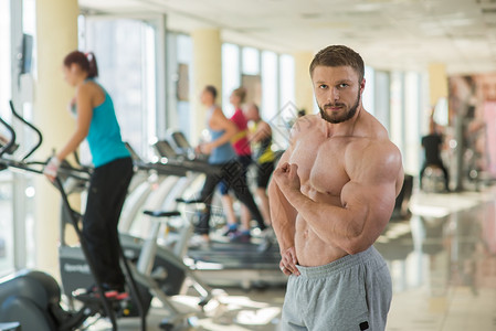 健身房里的肌肉男看照相机的强壮的人肌肉发达的躯干和手臂图片