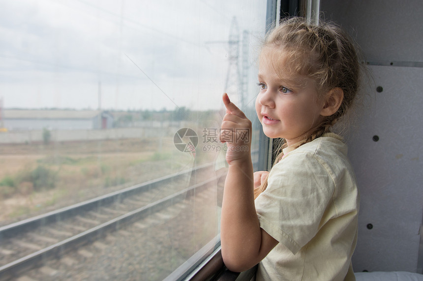 四岁女孩在二等列车中与货架底侧的窗外看望着窗户坐图片