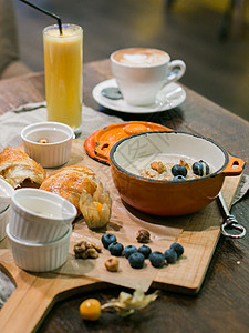 早餐加粥和羊角面包装上蓝莓果和坚果橙背景图片