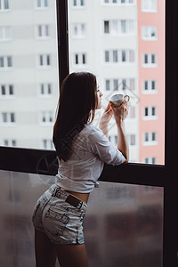 美丽的女孩在窗户边喝咖啡望背景图片