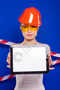 戴建筑头盔的女建筑师和蓝色背景上的防护眼镜图片