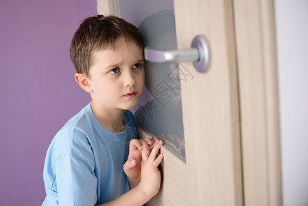 被吓坏了的孩子听一个家长在门口说话时用玻璃砸着他的耳朵图片