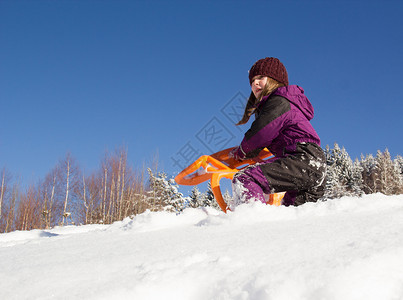 小女孩在雪橇上滑雪在山图片