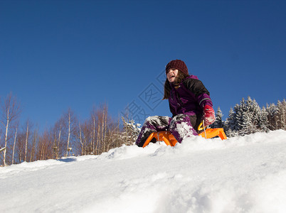 小女孩在雪橇上滑雪在山图片