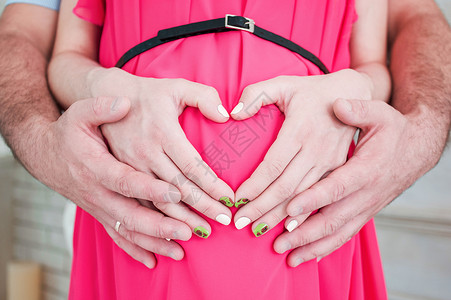 怀孕的心形手和她的丈夫在肚子上图片