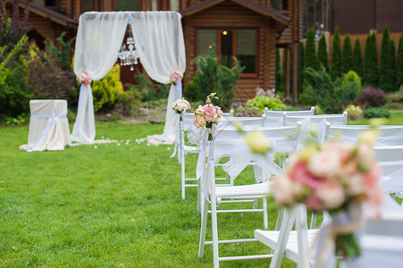 几把白色的椅子站在房子前面的绿色草坪上白色椅子上装饰着婚礼图片