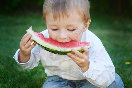 小男孩在夏日花园里吃西瓜图片