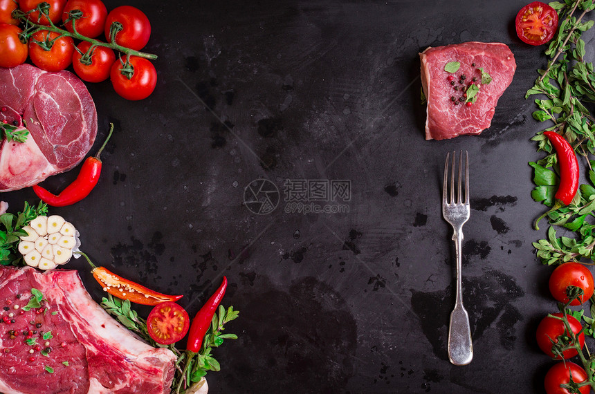 生多汁的肉牛排准备在黑色粉笔板背景上烤叉子上的肉小牛肉小腿ossobuco带骨肋眼牛排樱桃番茄鱼片图片