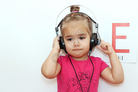 耳机里的漂亮小女孩听着白色背景的音乐上面写有E字母图片