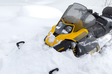黄色的雪地摩托停在一片深的雪堆里图片