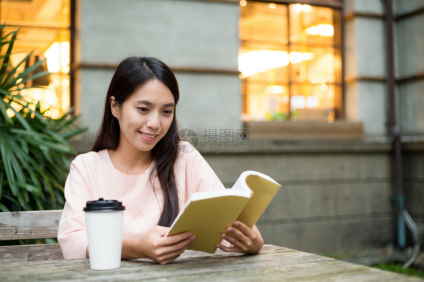 亚洲年轻女子在户外咖啡店看书图片
