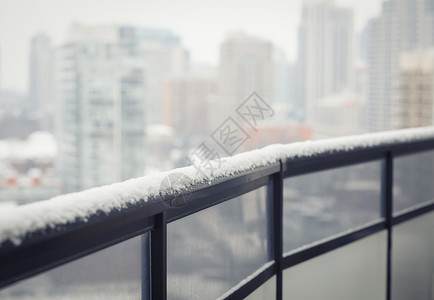 带玻璃的阳台黑色栏杆冬雪模糊的城镇背景文本的复制空间背景图片