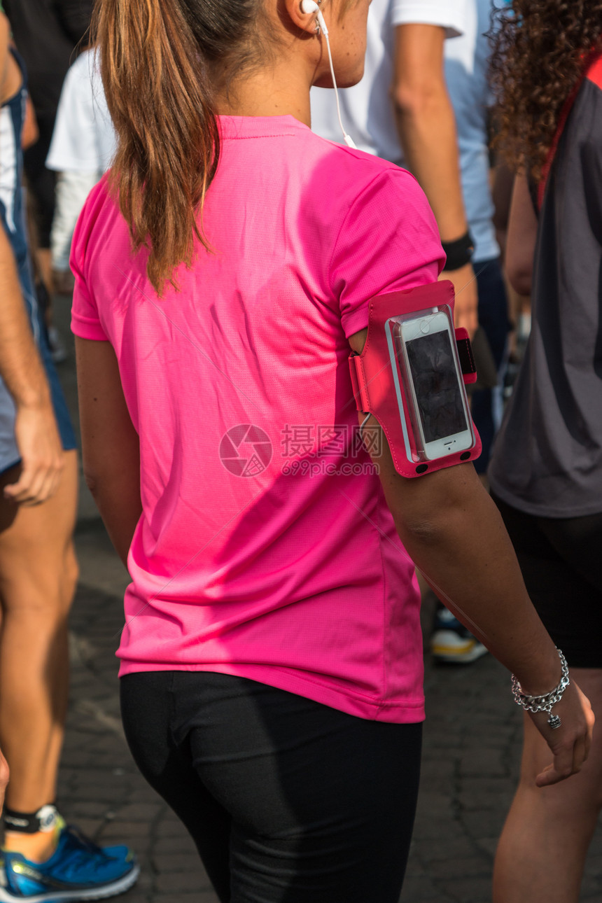 粉红T恤美女智能手机带箱子和耳机等市马拉松赛图片