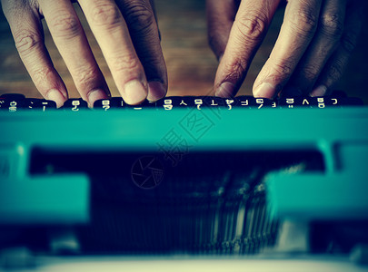 在旧蓝型打字机上打字的男子被关闭并图片