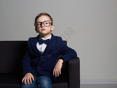 穿着西装戴眼镜的时尚小男孩在沙发上图片