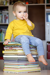 聪明的男孩坐在书堆上图片