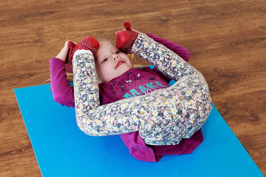 幼稚的健身小女孩正在垫子上做伸展运动图片
