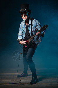 在深蓝色背景面前拿着电动飞吉他的高背景图片