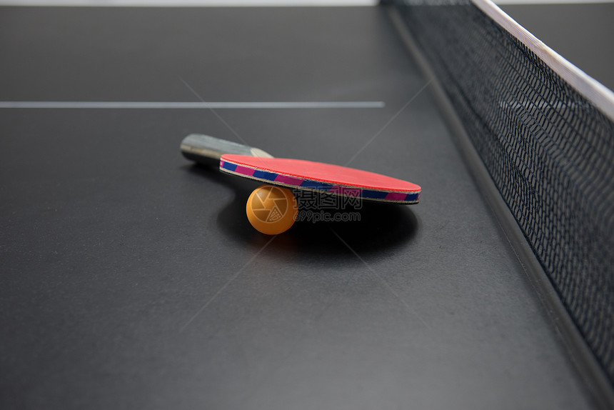 黑桌上有橙色球的乒乓球拍图片
