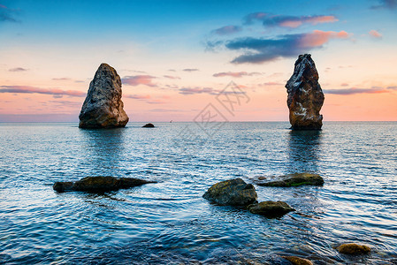 大岩石上方的海面日落风景与海岸图片