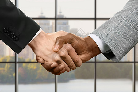 商人在总部握手城市背景下的商务握手白天的谈判很成功图片