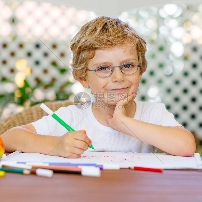在家做功课时戴眼镜的可爱快乐学龄前男孩的肖像图片