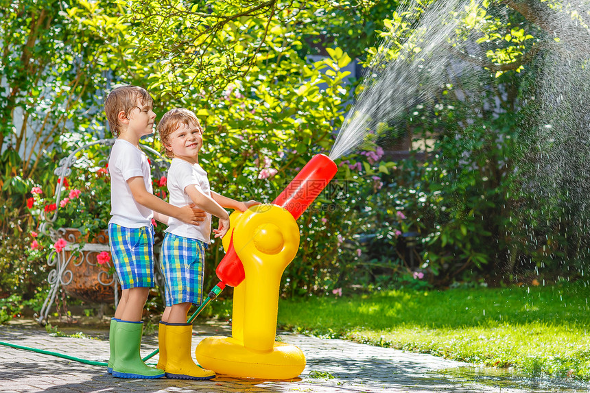 用花园软管泼水两个男孩在户外玩得开心有趣的户外图片