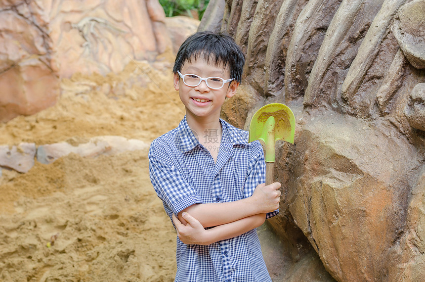 年轻亚洲男孩拿着铲子图片