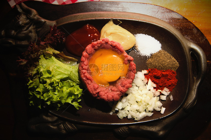 新鲜鞑靼牛肉配鸡蛋腌香料洋葱番茄酱和芥末的照片图片