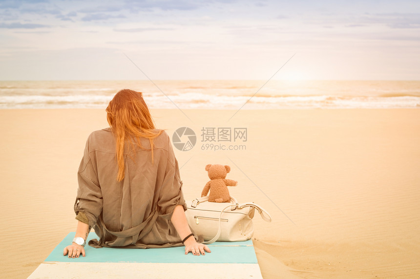 年轻的单身女坐在沙滩上图片
