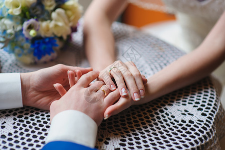 男人和女人的手放在咖啡馆的桌子上新娘和新郎手牵花边桌布图片