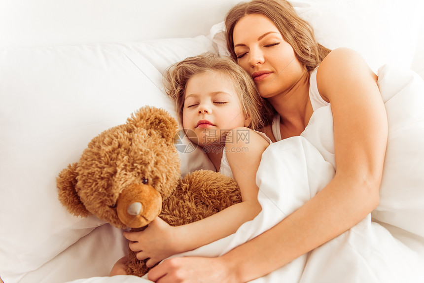 甜美的小女孩和她美丽的年轻妈在家睡觉时和泰图片