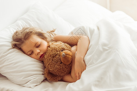 可爱的小女孩抱着一只泰迪熊睡在图片