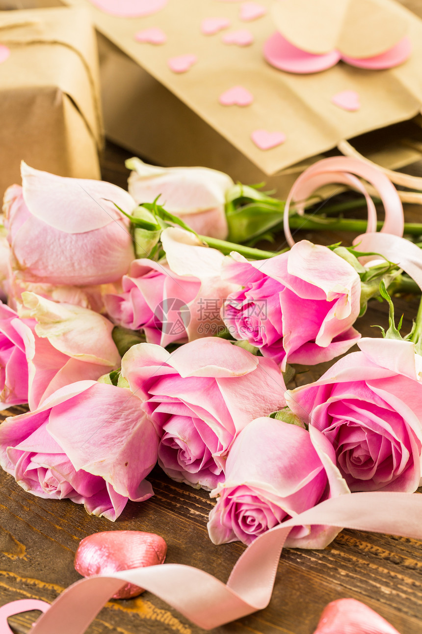 粉红玫瑰和礼物包装在生锈木板图片