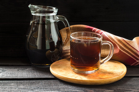 俄罗斯传统饮料用面包黑麦糖和水制成的Kvas罐子和杯子在黑暗木质背景图片