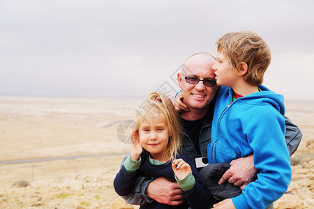 父亲和两个孩子在沙漠里图片