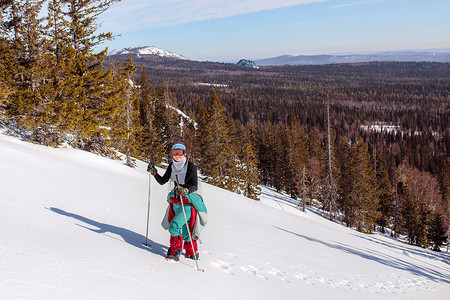 一位身着红衣的女登山者爬上雪地的山坡冬天清空天日在乌拉尔图片