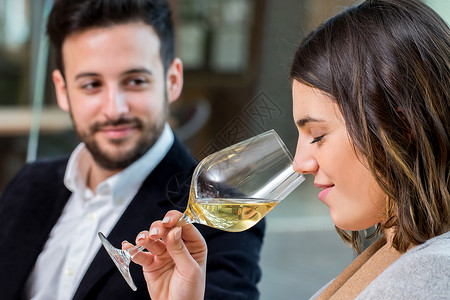 闻着白葡萄酒香味的年轻女子在品尝时图片