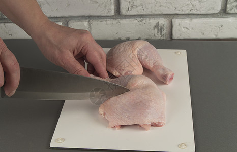 鸡煮鸡腿女人用刀切背景图片