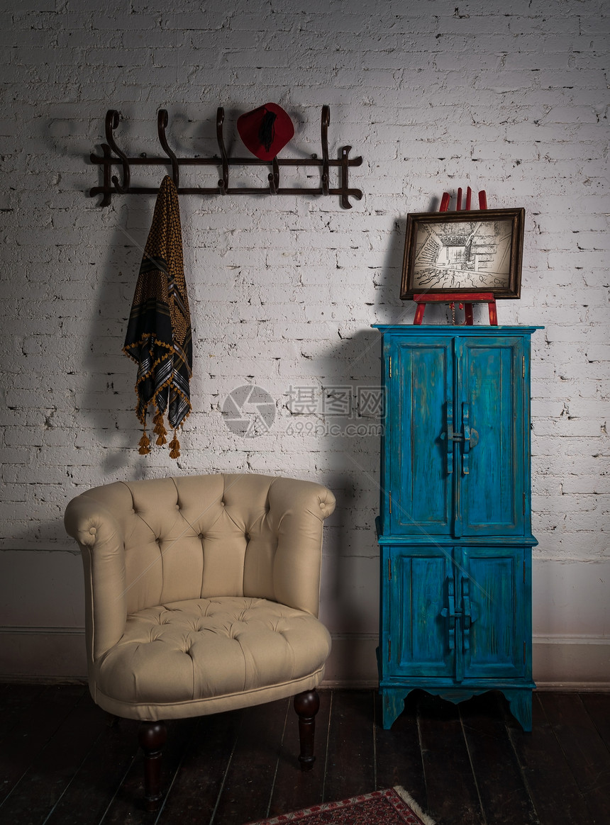 古老的海蜂臂椅旧的蓝橱柜挂有围巾或围巾和红面纸的挂墙板以及图片