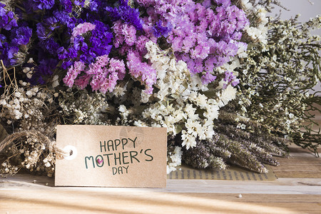 木桌上放着一束带母亲节卡片的干花图片