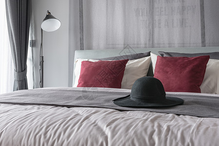 用红色枕头设计现代卧室设计的床上黑帽子图片