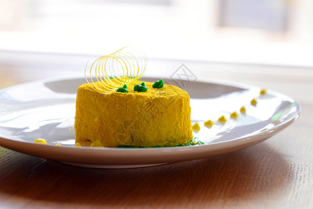 白盘上有绿色装饰的黄色蛋糕图片