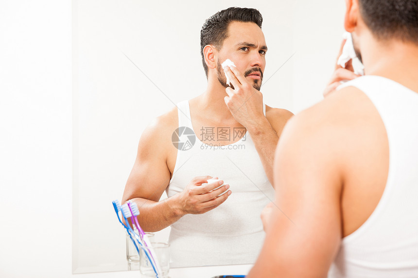 一个英俊的年轻人把剃须膏涂在脸上图片