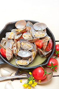 用铁锅炖新鲜的蛤蜊放在质朴的木桌上图片