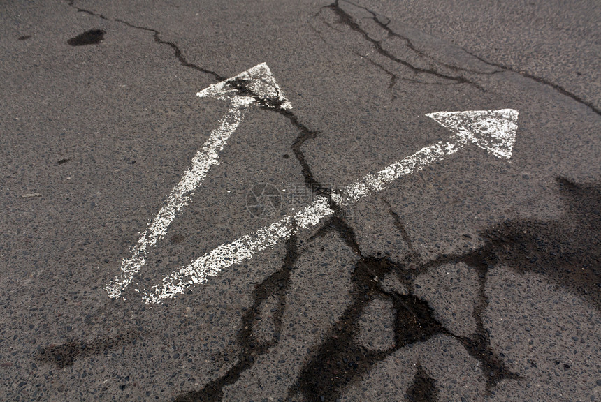 肮脏的沥青表面上的两个白色箭头交通标识图片